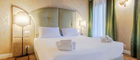 Una habitació d'hotel amb un llit gran, dues làmpades de nit, una tauleta de nit i una lluminària penjada a la paret.