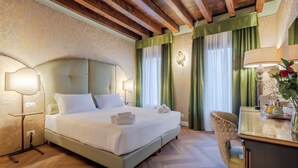 A hotel room with a large bed, a desk with a lamp, and a chair. - 312 Piazza San Marco (Venice)