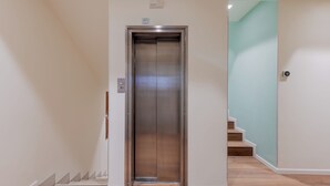 A modern elevator in a hallway with a wooden floor and a light blue wall. - 312 Piazza San Marco (Venice)