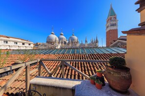 A rooftop terrace with terracotta tiles, potted plants, and a view of historic domed buildings and a tower. - 312 Piazza San Marco (Venice)