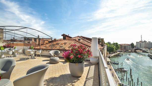 A rooftop terrace with outdoor seating, a view of the city, and a river. - Venetian Palace Gold Apartment with Balcony R&R (Venecia)