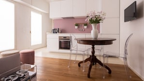 A modern kitchen with white cabinets, a pink backsplash, and a round wooden table with clear chairs. - Venetian Palace Gold Apartment with Balcony R&R (Venecia)