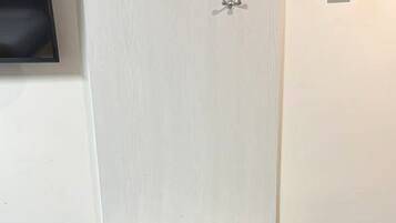 Ein Badezimmer mit einem Holzbadschränken, zwei Handtuchhaltern und einem digitalen Thermostat an der Wand.