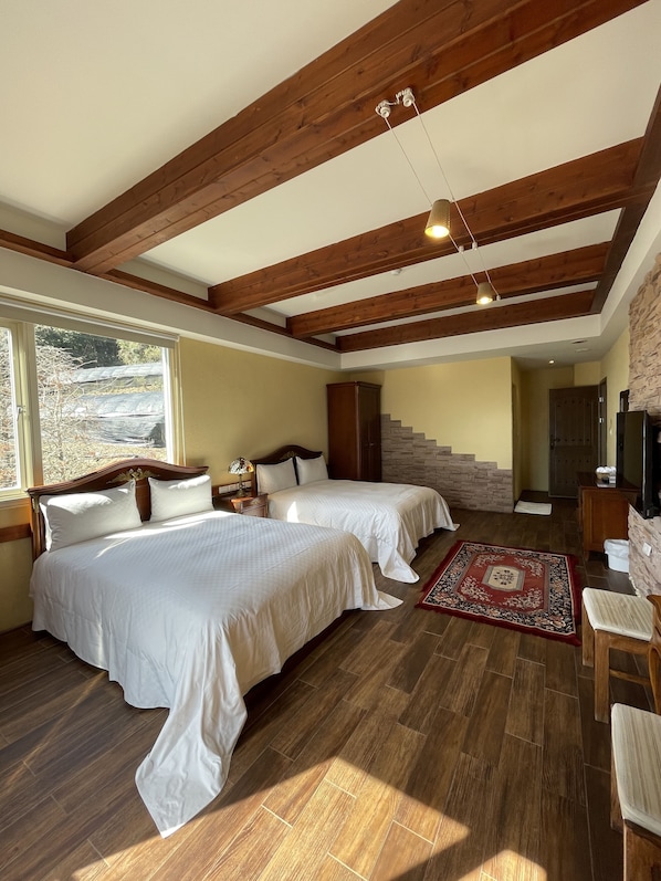 Un dormitorio con dos camas, vigas de madera, una pared de piedra y vistas al exterior.