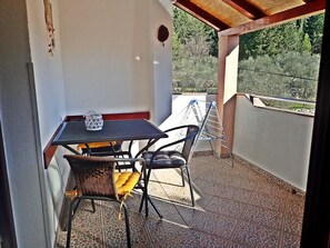 Un balcon avec une table et des chaises, un étendoir et une vue sur la verdure.