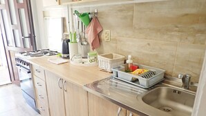 Una cocina moderna con armarios de madera, un lavamanos de acero inoxidable y diversos utensilios y electrodomésticos.
