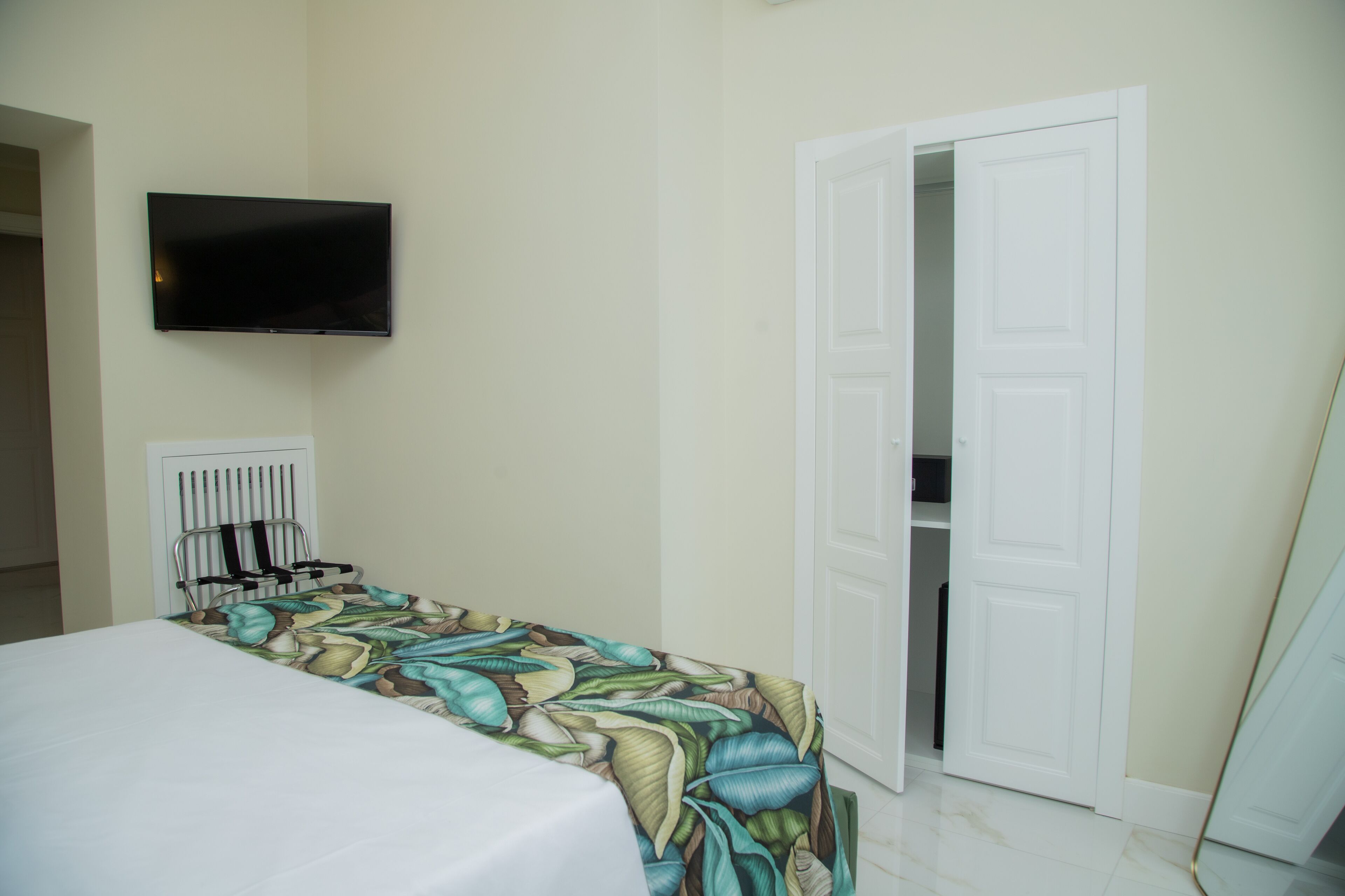 Una camera da letto con un letto, una televisione montata a parete e una porta che dà su un armadio.