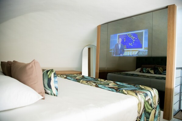 A hotel room with a bed, a large mirror, and a television screen displaying a news broadcast.