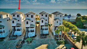 A coastal hotel with multiple white buildings, a central staircase, and a view of the ocean.