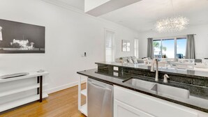 A modern kitchen with a dishwasher, a sink, and a dining area with a table and chairs.