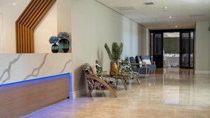 A modern reception area with a marble reception desk, patterned chairs, and a potted plant. - 12 Oceans Hotel and Conference Centre (Kingsburgh)