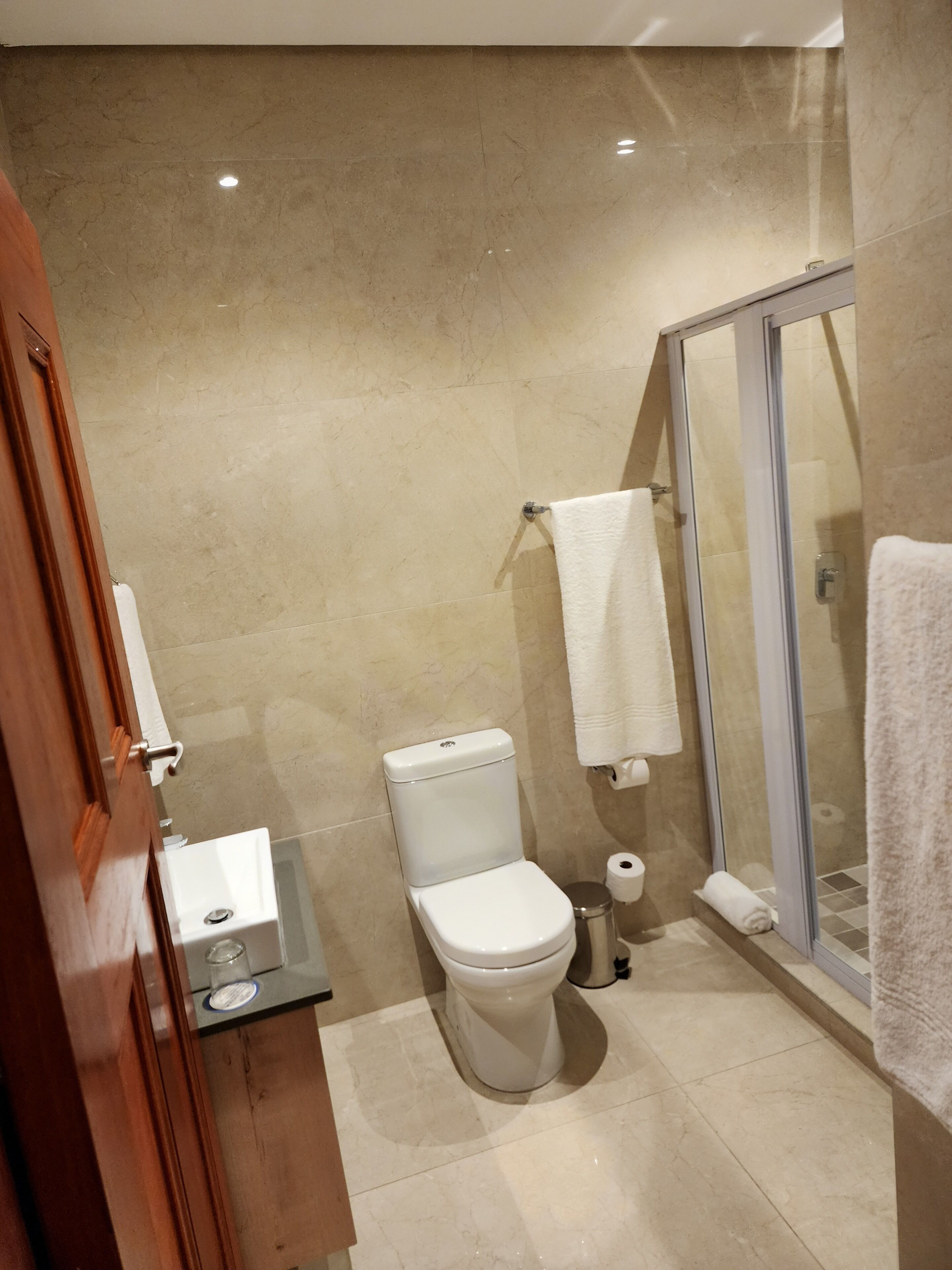 Un baño moderno con inodoro, lavamanos y cabina de ducha de vidrio.