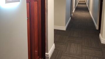 Un pasillo de hotel con piso alfombrado, puertas de madera y un letrero que indica la habitación 1202.