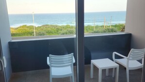 A balcony with two white chairs and a small table, overlooking a beach with the ocean and greenery. - 12 Oceans Hotel and Conference Centre (Kingsburgh)