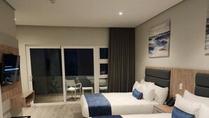 A hotel room with two beds, a TV, a desk, and a sliding door to a balcony. - 12 Oceans Hotel and Conference Centre (Kingsburgh)