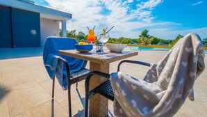 An outdoor seating area with a table, chairs, and a view of a swimming pool. - Hotel Delfin Lanterna (Tar-Vabriga)