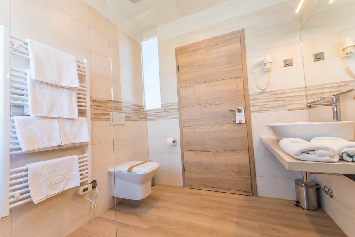 A modern bathroom with a wooden door, a white sink, and a towel rack.