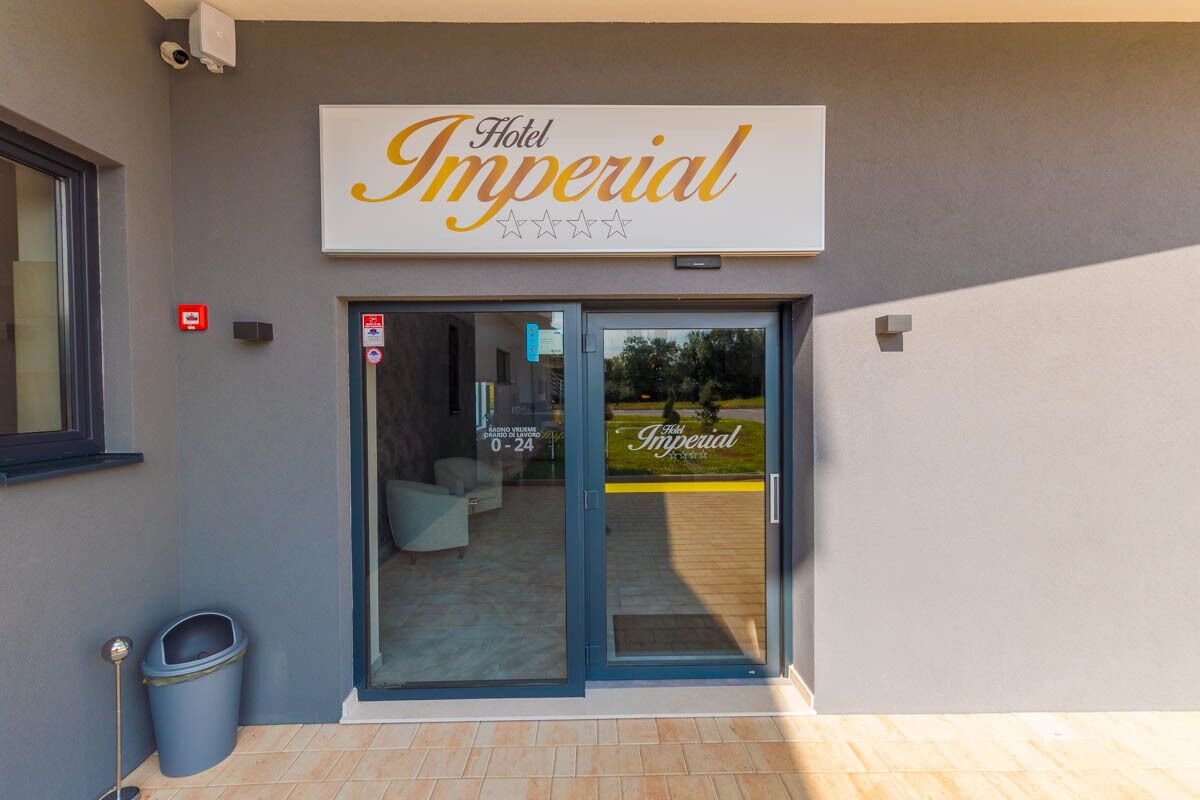 L’entrée de l’hôtel Imperial se compose d’une porte vitrée, d’une poubelle et d’une enseigne placée au-dessus de la porte.