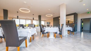 A modern dining area with multiple tables and chairs, large windows, and a clean, minimalist design. - Hotel Delfin Lanterna (Tar-Vabriga)