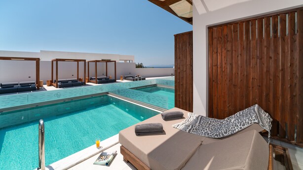 A poolside area with lounge chairs and a wooden deck overlooking a clear blue sky. - Theretra Pefki Seaside (Rhodes)