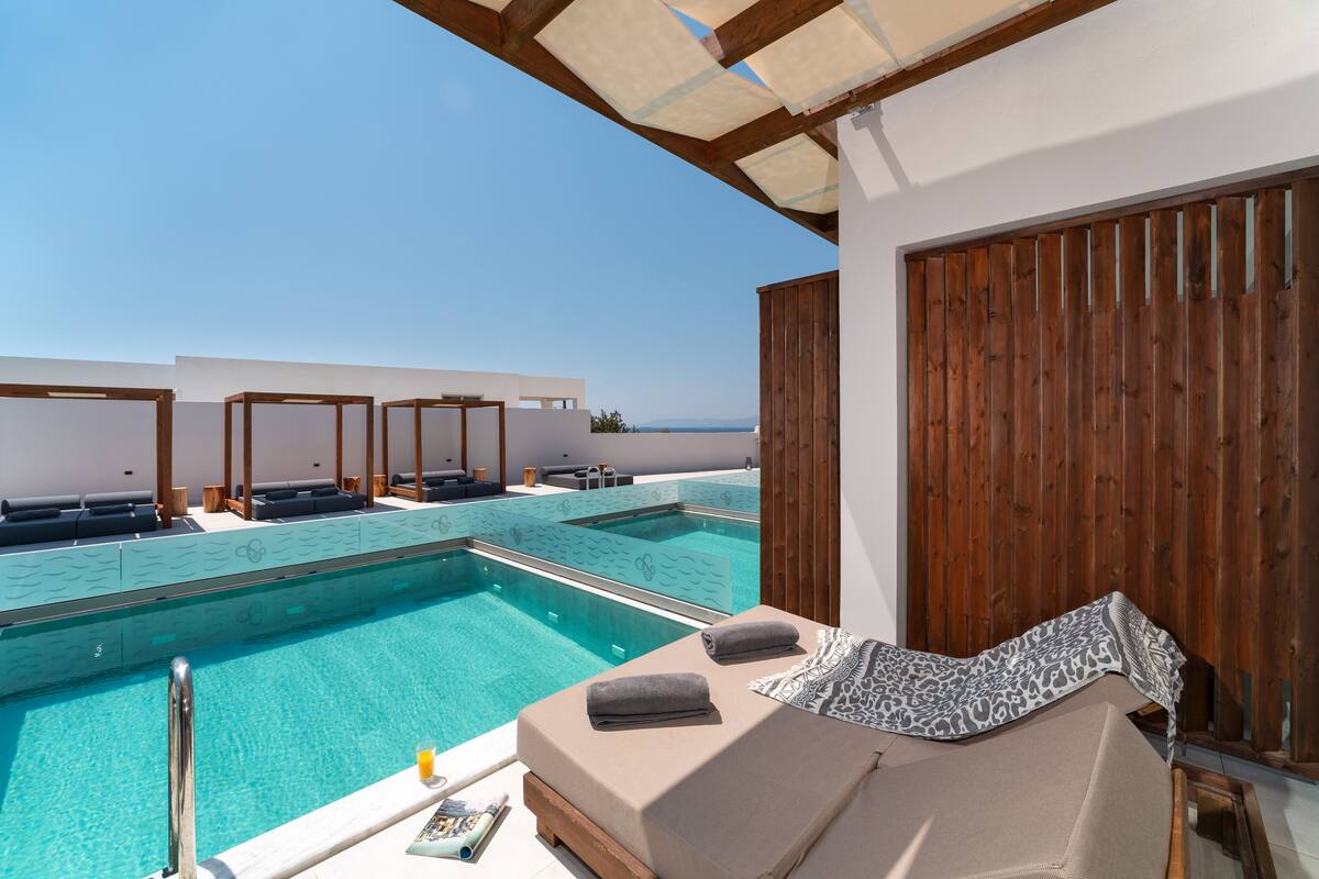 A poolside area with lounge chairs and a wooden deck overlooking a clear blue sky.