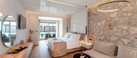 A modern bedroom with a bed, a sofa, a small table, and a stone wall.
