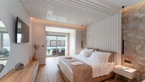 A modern bedroom with a large bed, bedside tables, and a view of the outdoors. - Theretra Pefki Seaside (Rhodes)