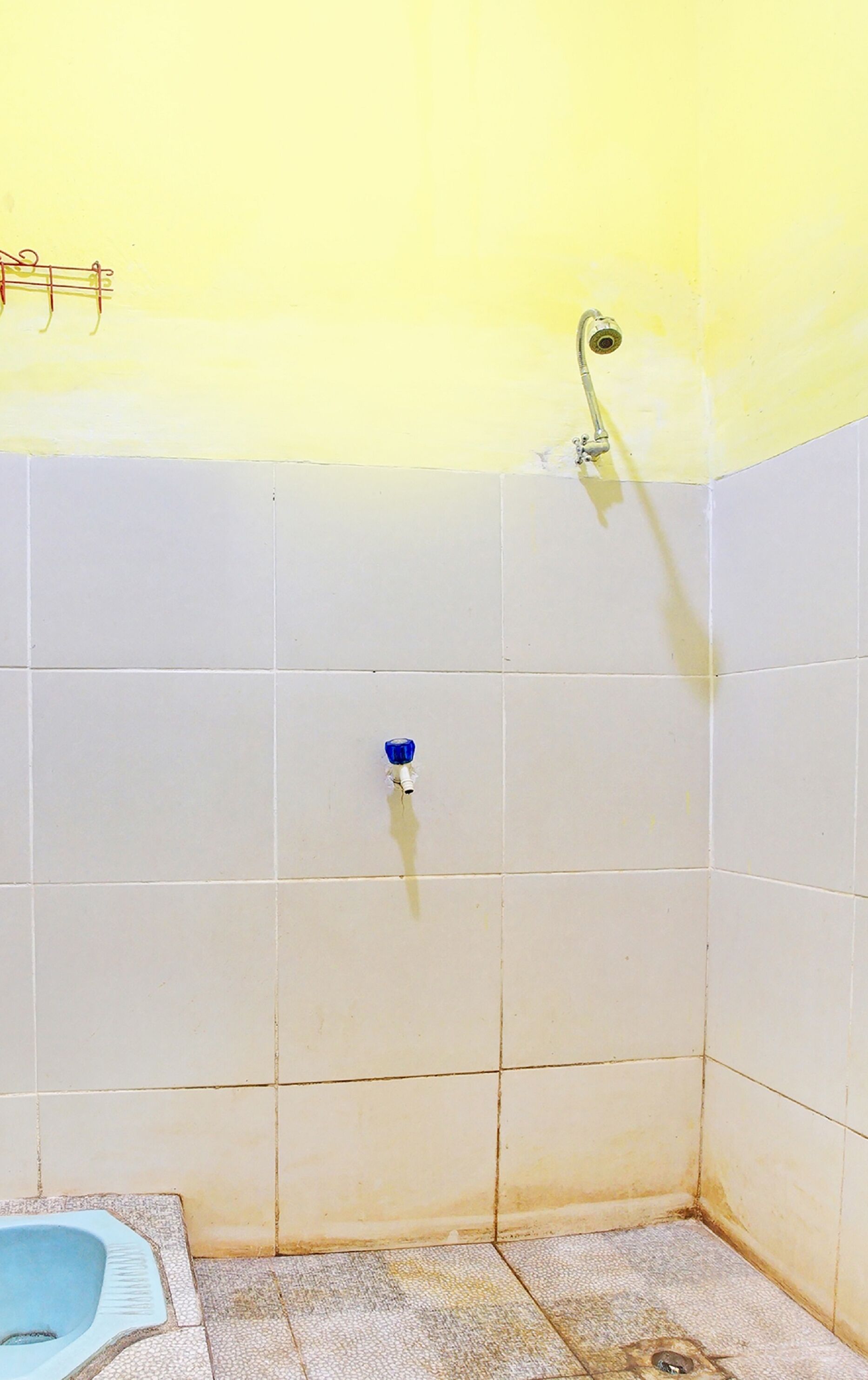 A small bathroom with a shower, a toilet, and a blue faucet.