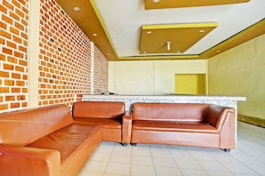 Un interior moderno con una pared de ladrillo, un sofá de cuero marrón, una zona de cocina y una pared de acento amarilla.