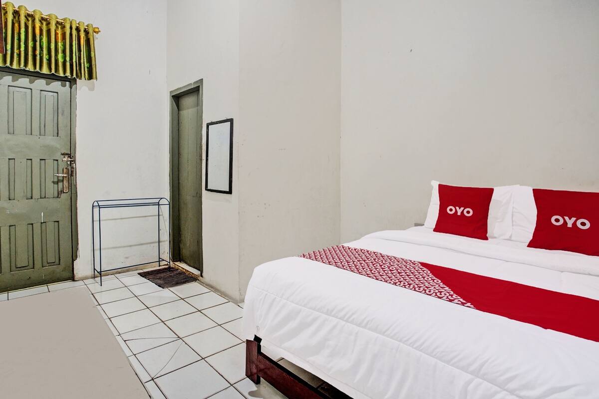 Une chambre à coucher avec un lit, une porte, une petite table et un tableau accroché au mur.