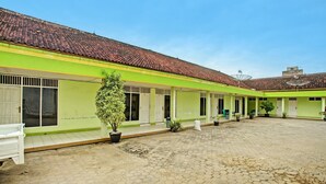A courtyard with a green building, tiled roof, and potted plants.