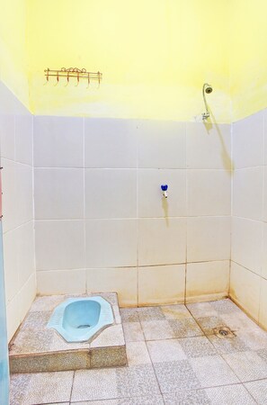 Un baño pequeño con paredes de azulejos, un inodoro pedestal, una ducha y un perchero para toallas.