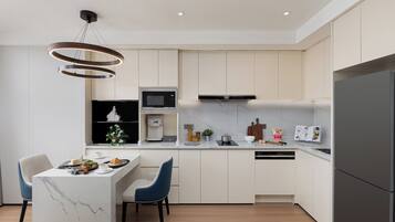 A modern kitchen with a marble island, a built-in microwave, a coffee machine, and a refrigerator.