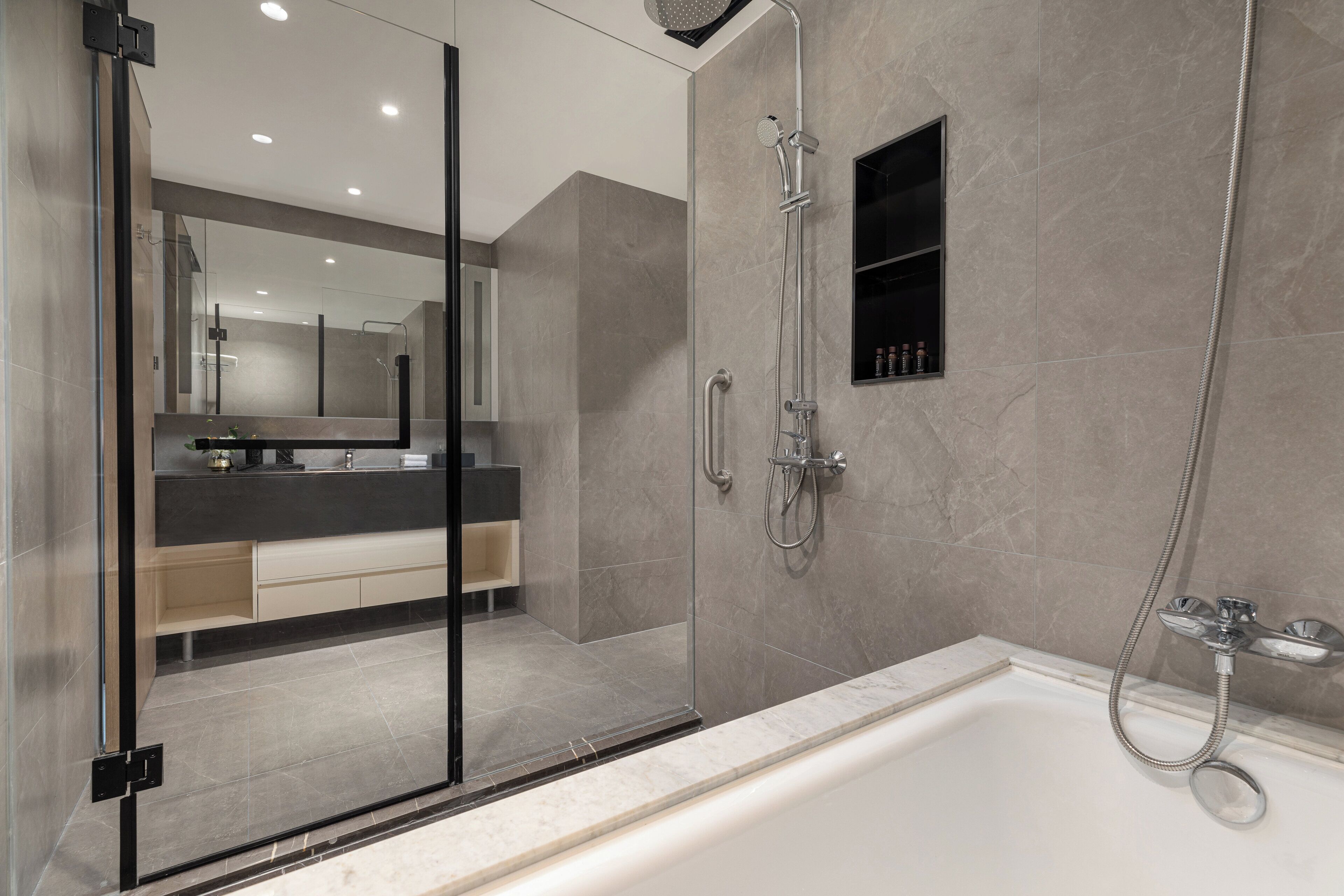 Un bagno moderno con doccia vetro, vasca e mobile lavabo con specchio.