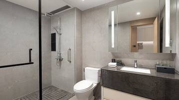 A modern bathroom with a glass-enclosed shower, a toilet, and a vanity with a large mirror.