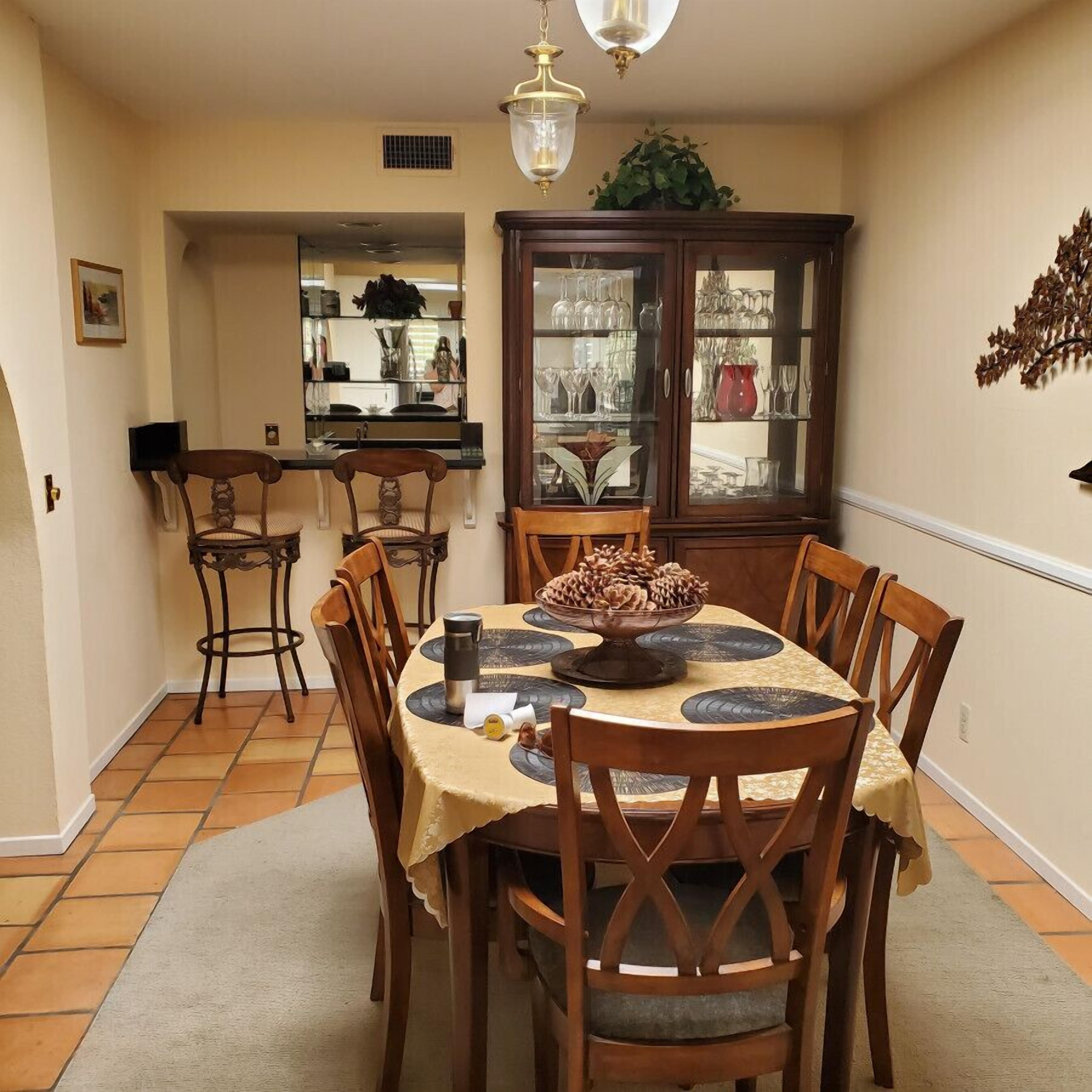 Ein Essbereich mit einem runden Tisch, Holzstühlen, einem Schrank mit Glastüren und einer Pendelleuchte.