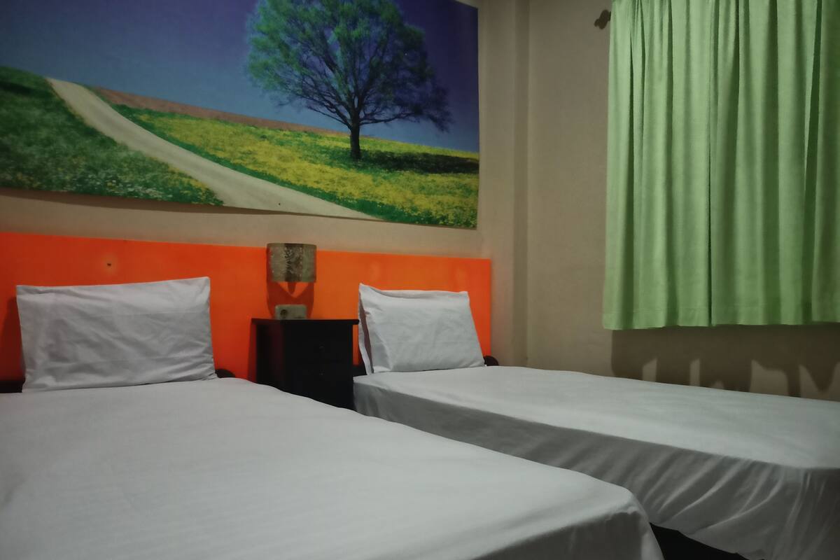 Une chambre d’hôtel avec deux lits, une table de chevet et une fresque murale.