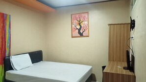 Une chambre à coucher avec un lit, une commode en bois, un tableau représentant un arbre et un rideau.