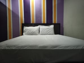 Una cama con ropa blanca en una habitación con paredes a rayas.