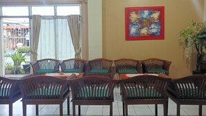Un coin repas avec des chaises et des tables en bois, une grande fenêtre avec des rideaux et un tableau accroché au mur.