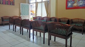 Une salle avec des chaises en bois disposées en rangées, un tableau blanc et deux tableaux accrochés aux murs.