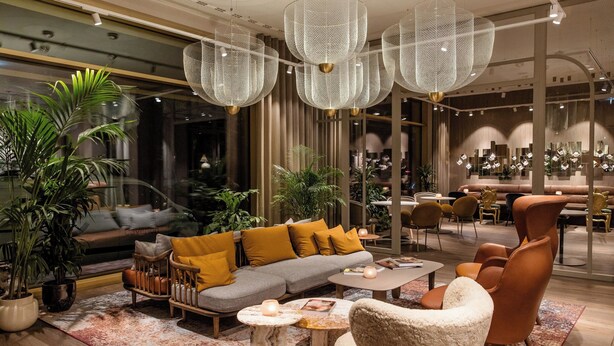 Un interior moderno con un sofá gris, sillones naranjas y una mesa de centro.