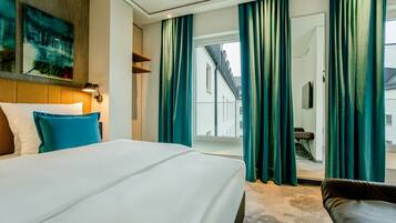 Une chambre d’hôtel avec un grand lit, des rideaux de couleur turquoise, une vue sur l’extérieur et un design moderne.