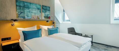 Une chambre d’hôtel avec un lit, des tables de chevet, un bureau, une chaise et une fenêtre.