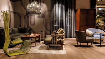 A modern living room with a sofa, a green chair, a wooden coffee table, and a hanging light fixture.