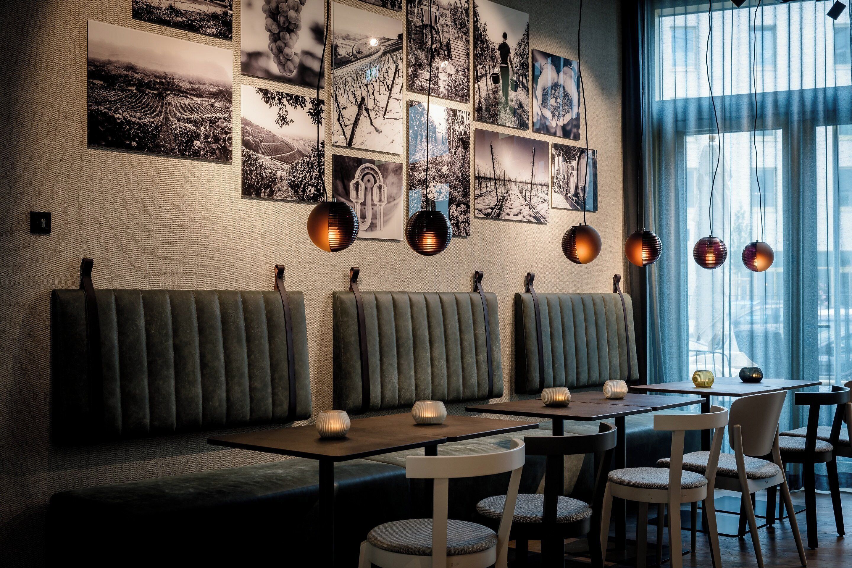 Ein Restaurant mit Sitzecken, Tischen und hängenden Pendelleuchten.