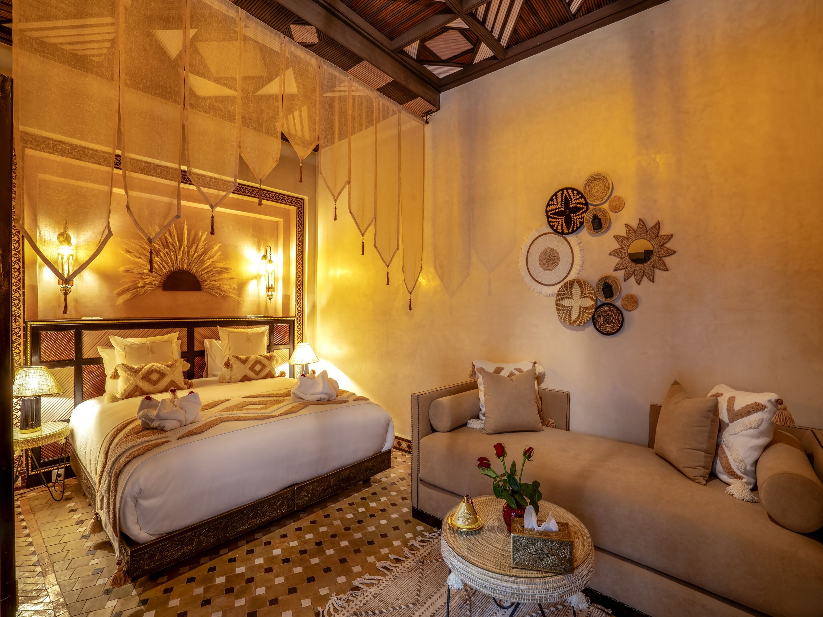 A well-lit bedroom with a large bed, a sofa, and decorative wall art.