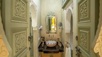 A bathroom with ornate doors, a sink with a bowl, a mirror, and a shower.