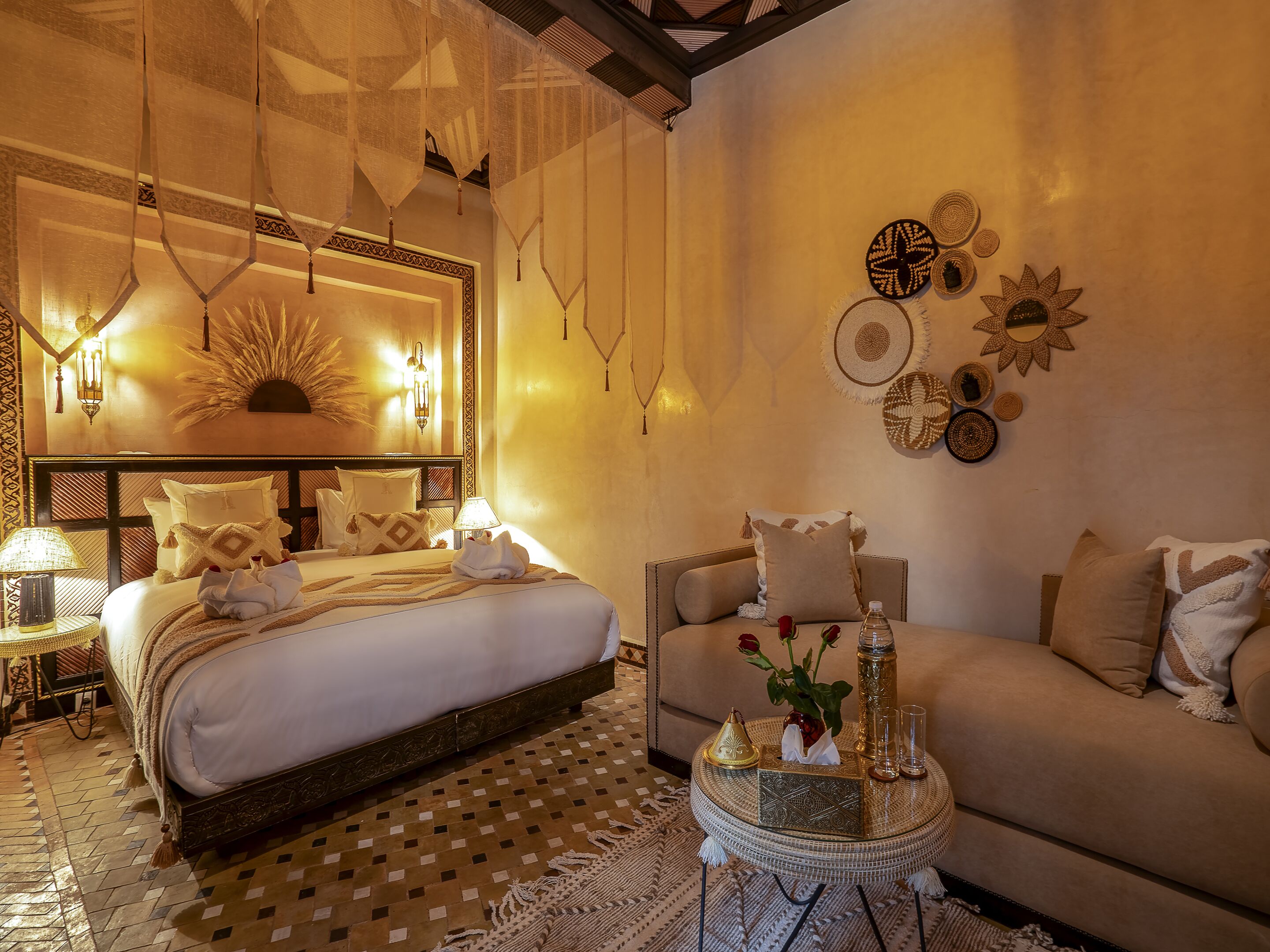 A well-appointed bedroom with a large bed, a sofa, decorative wall art, and a patterned floor.