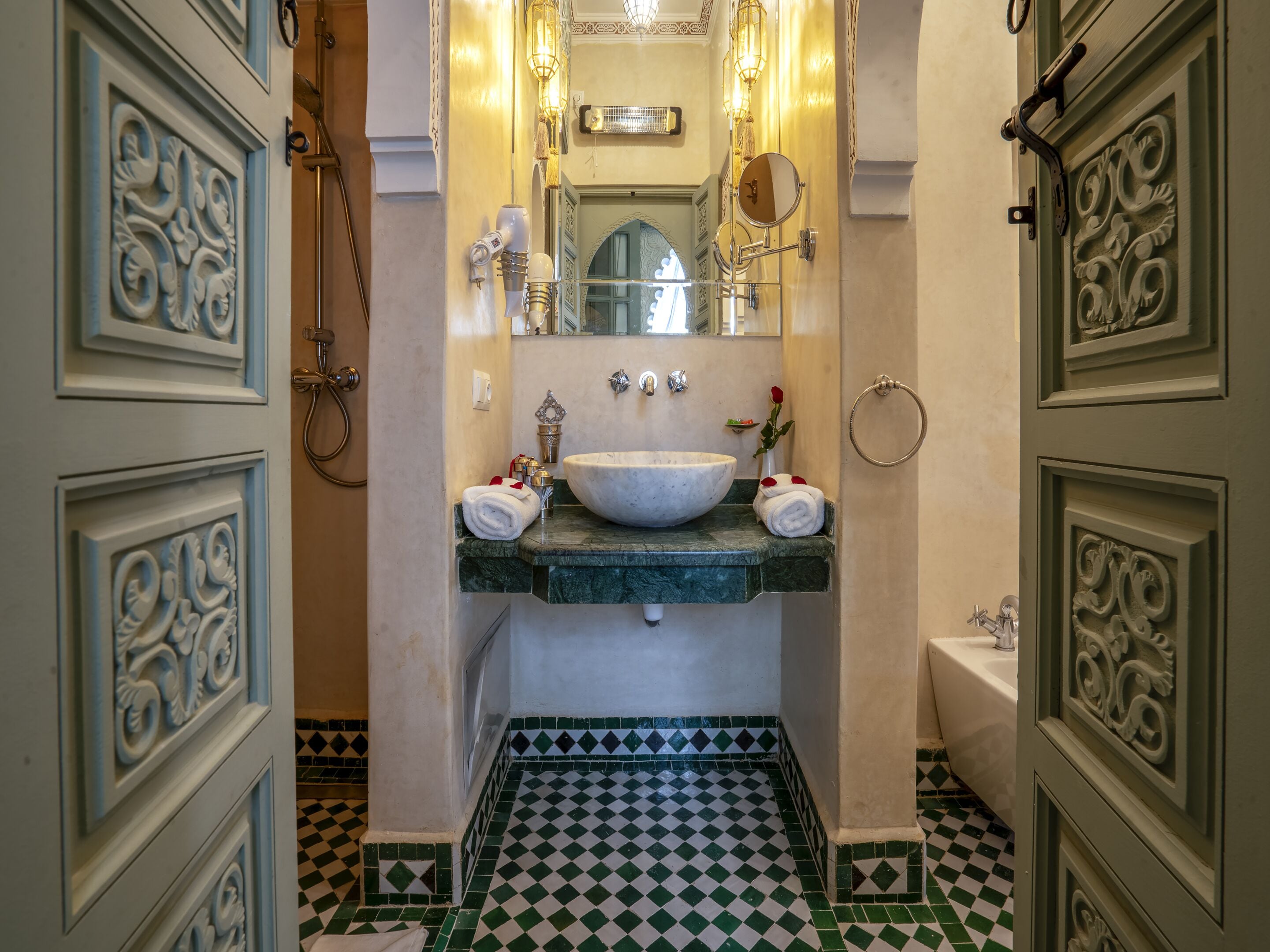 A bathroom with a large white sink, a mirror, and a toilet. The floor has a checkered pattern, and the walls have decorative molding.